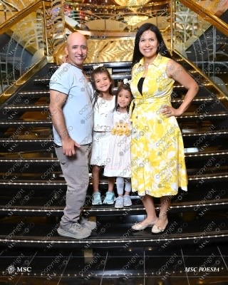 Family of four posing on the grand staircase aboard MSC Poesia during an Alaska cruise.